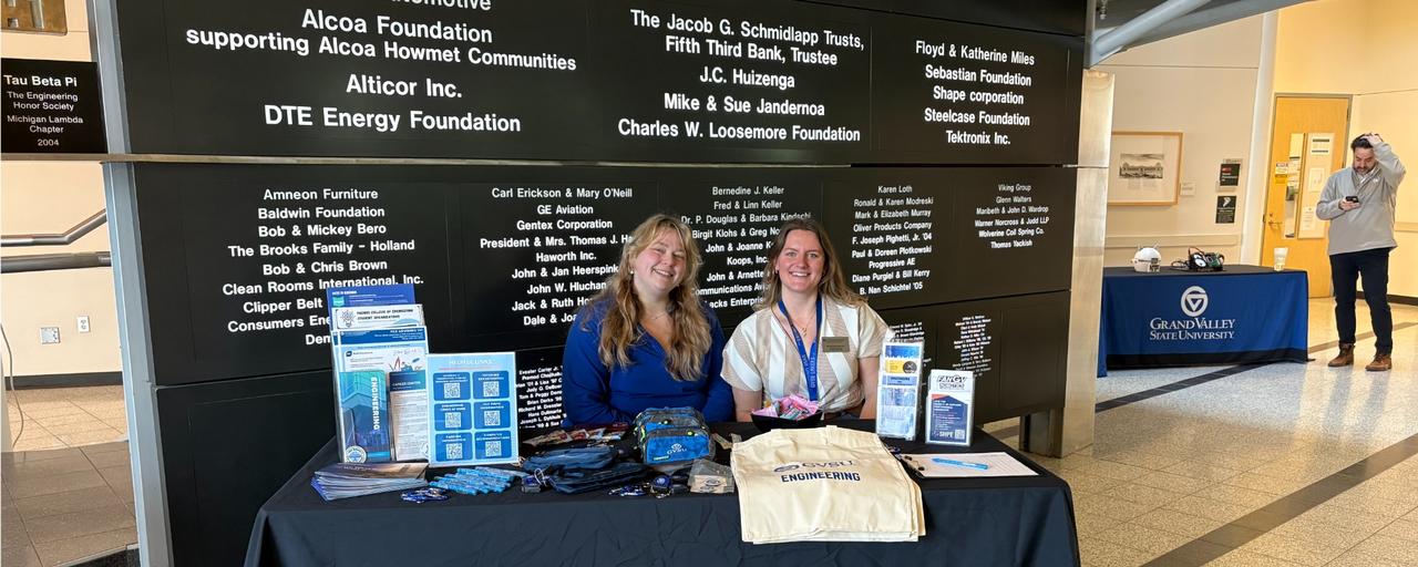 Two female employees pictured tabling for a college visit.